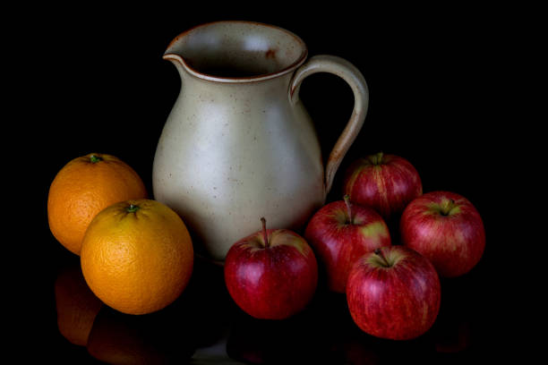 istock Earthenware Jug with Apples and Oranges on a Shiny Black Surface 1407303555