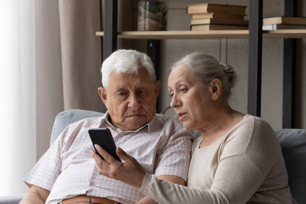 istock Senior couple discuss mobile app seated on sofa at home 1407303701