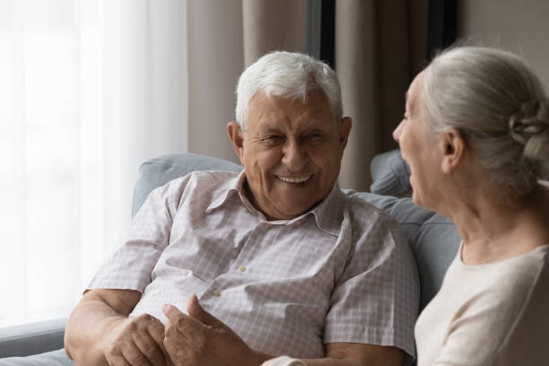 istock Older couple relaxing on sofa laughing talking feel happy 1407303703