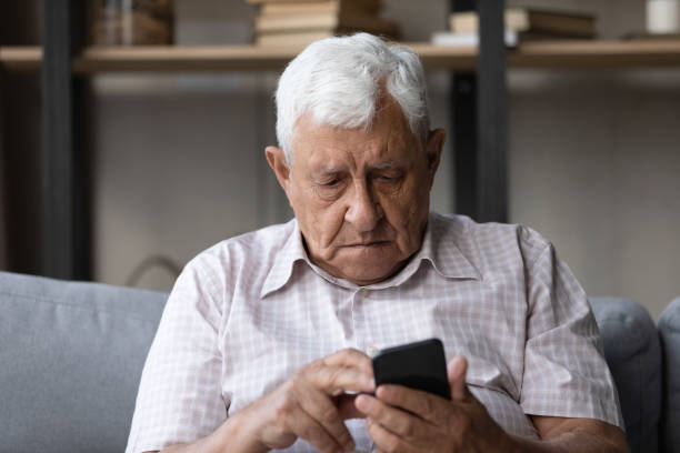 istock Senior man holds smartphone staring at screen feels concerned 1407303771
