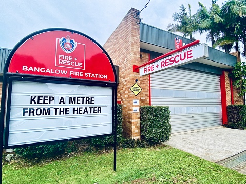 Horizontal front entrance of Australian rural fire and rescue department on public street with sign regarding prevention of winter fire heater accidents ‘a metre from the heater’ at Bangalow fire station near Byron Bay NSW Australia