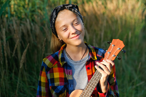 Defocus girl with guitar. Teen girl walking on nature background. Little kid girl outside. Green meadow. Generation z. Autumn. Bandana. Lifestyle. Dreamy smiling fashion kid. Out of focus.
