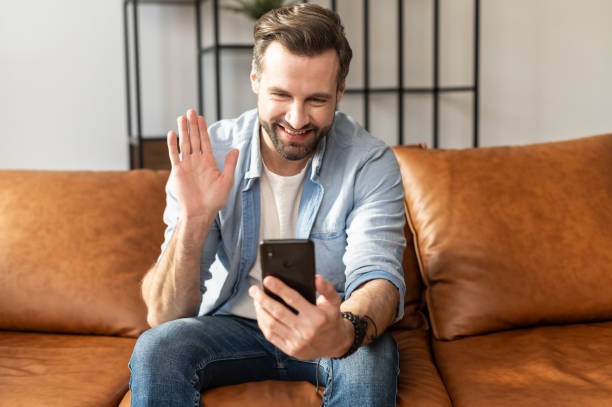 istock Smiling hipster man waving at mobile phone 1407308827