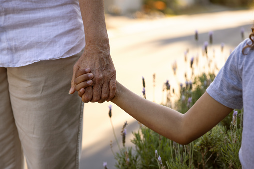 Grandmother and a grandchild holding hands by their house