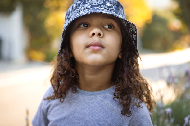 Portrait of a bored girl wearing a hat and standing outside during magic hour