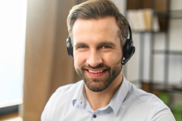 istock Handsome European man operator looking away and talking by headset 1407308912
