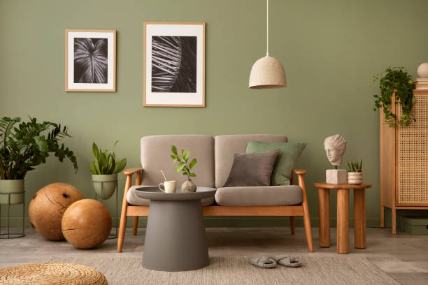 istock Elegant composition of living room interior. Modern scandi sofa, side table, rattan commode, plants and creative personal accessories. Sage green wall. Template. Copy space. 1407309565