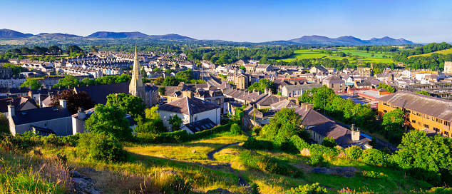 A view to Caernarfon from Twt Hill with houses and a church, and the mountains of Snowdonia in the background