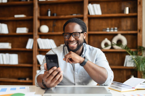 istock Portrait of black entrepreneur in office watching at phone while working 1407309732