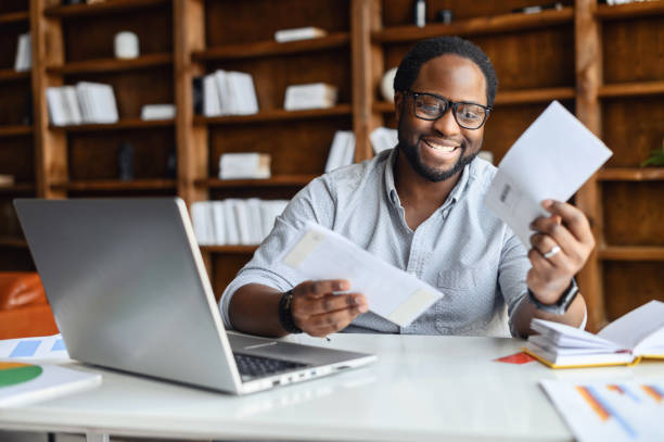 istock Smiling black man in the office received mailing envelopes 1407309741
