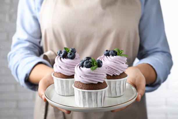 istock Woman holding plate with sweet cupcakes, closeup 1407310621