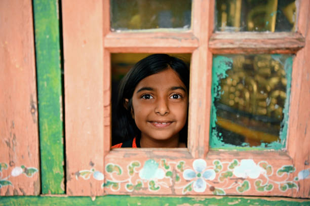 A cute girl looking out from the old window frame of a Monastery, Pelling, Sikkim