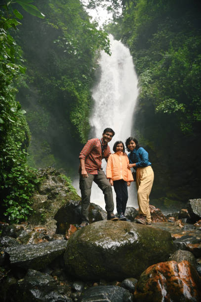 istock Family posing for a photograph while enjoying at a majestic waterfall 1407310772