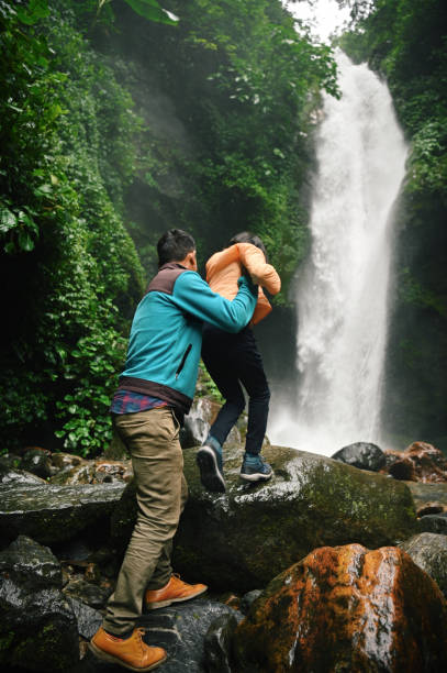 istock Man assisting a girl toward a waterfall 1407310778