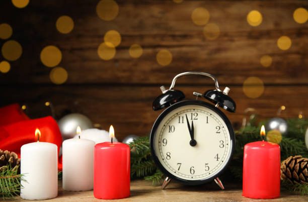 istock Alarm clock, burning candles and Christmas decor on wooden table, bokeh effect 1407310865