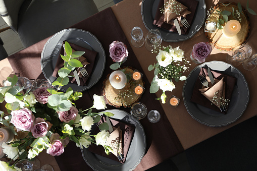 Festive table setting with beautiful tableware, candles and floral decor indoors, top view