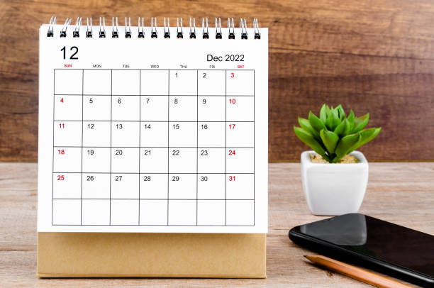 the december 2022 desk calendar on wooden table. - december stockfoto's en -beelden