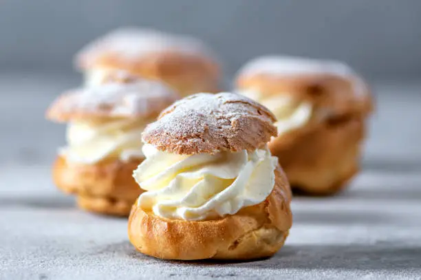 Homemade profiteroles with cream on light background