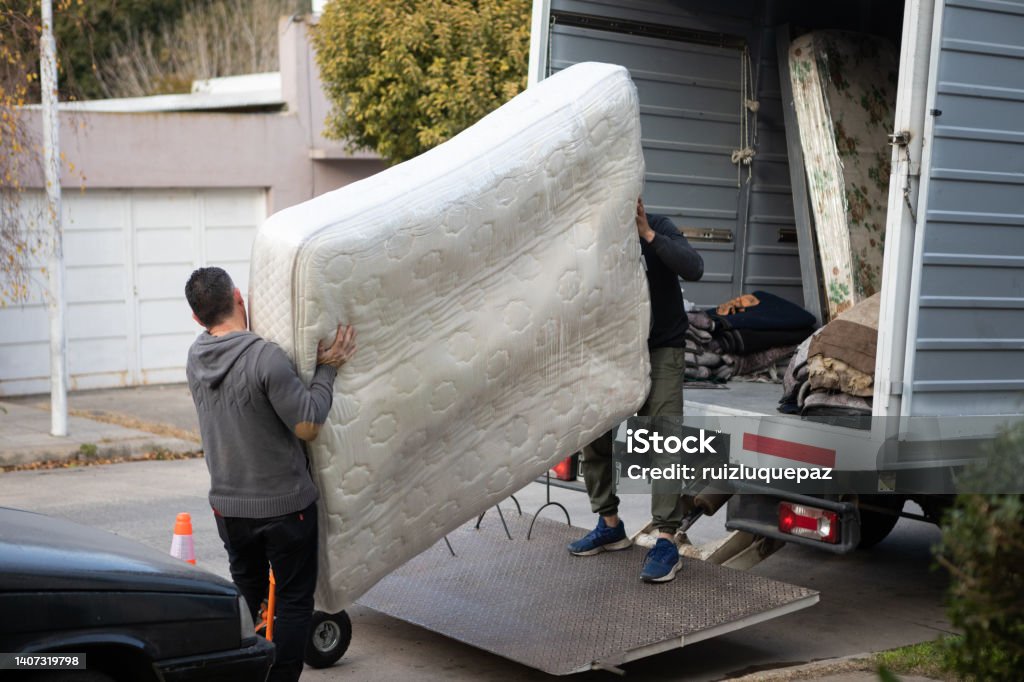 House moving process. Owner and moving staff packing, protecting and transporting furniture and movables to moving truck House moving process. Packaging and transportation to moving truck Moving Van Stock Photo