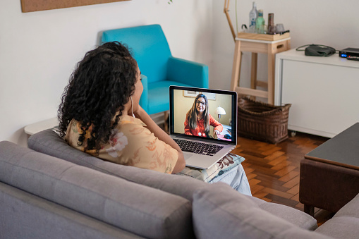 African Amican young woman talking to psychologist in video conference