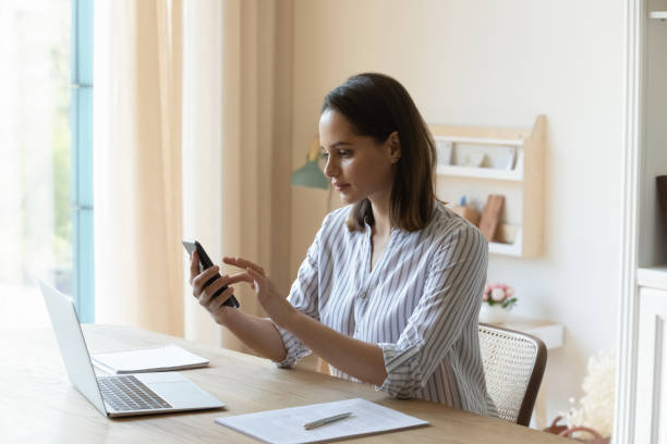 istock Happy pretty young woman using cellphone, distracted from laptop work. 1407322112