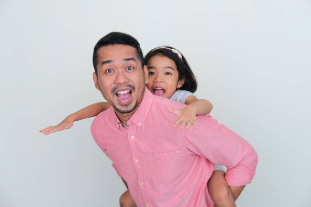 A father carry his daughter in his back with excited expression A father carry his daughter in his back with excited expression keluarga stock pictures, royalty-free photos & images