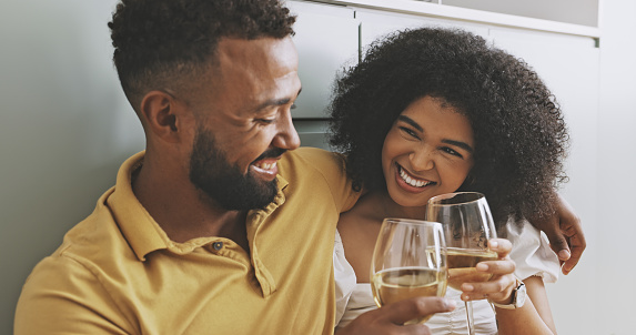 Couple toasting and drinking wine. Husband and wife having a drink and celebrating their relationship. Girlfriend and boyfriend bonding. Man and woman giving each other a toast while holding glasses