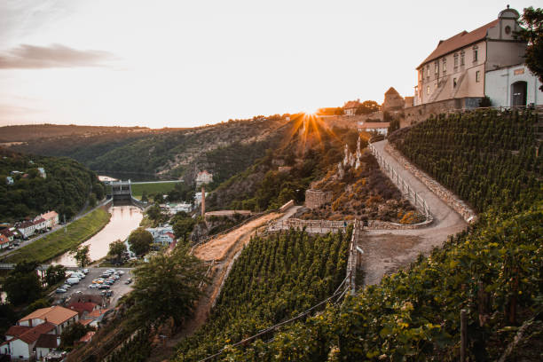 Sunset in the city of Znojmo in the South Moravian region in the Czech Republic. View of the castle and dam and vines on the hillside. Orange light illuminates the whole scenery stock photo