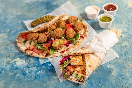 Traditional Mediterranean Arabic grilled halloumi and falafel, hummus and vegetables in flatbread wraps with herbs and a variety of sauces