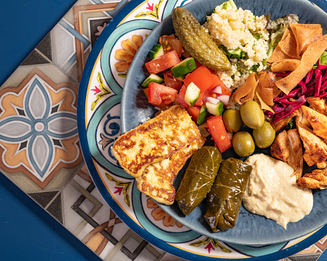 In this vibrant image, a feast for the senses unfolds before your eyes. The focal point is a plate filled with an assortment of colorful, mouthwatering delicacies. The plate is adorned with an array of fresh, aromatic ingredients that reflect the rich and diverse culinary traditions of Greece.