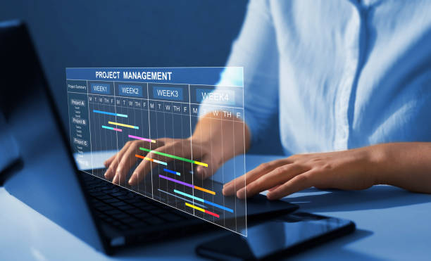 Project manager working on laptop and updating tasks and milestones progress planning with Gantt chart scheduling interface for company on virtual screen. Business Project Management System. stock photo