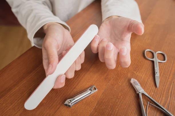 Close-up of hand of caucasian young woman doing manicure at home with nail supplies. stock photo