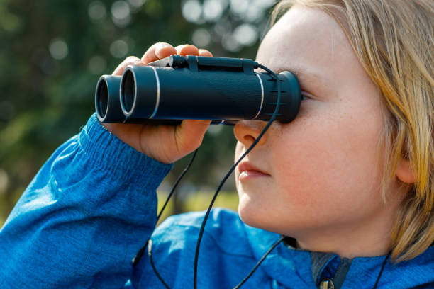 niño mirando a través de binoculares en el parque. niño explorando la vida silvestre. observación de aves y aventura - discovery binoculars boy scout searching fotografías e imágenes de stock