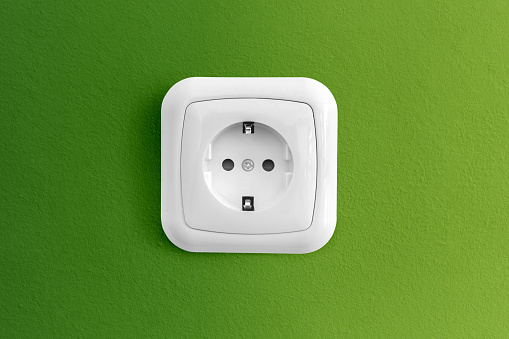 Multiple plugs in wall electrical outlet is dangerous overload, close-up with copy space