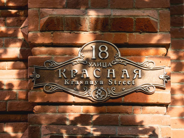 Old fashioned sign of Krasnaya street. Sunlight on red brick wall and vintage street pointer. Krasnodar, Russia - June 02, 2021. Old fashioned sign of Krasnaya street. Sunlight on red brick wall and vintage street pointer. krasnodar stock pictures, royalty-free photos & images