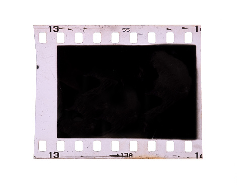 Detailed photograph of 35mm film shot in a lightbox with a studio light effect of a metal-bodied analog camera and its lens