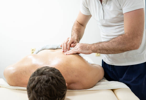 istock Caucasian physiotherapist massaging a customer with his hands on a massage table in his home salon. 1407345178