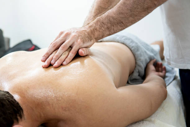 istock Caucasian physiotherapist massaging a customer with his hands on a massage table in his home salon. 1407345314