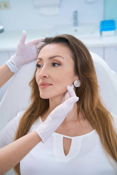 istock Female doctor examining lady face with both gloved hands 1407346383