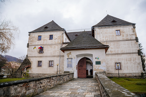 Jesenik, Moravia, Czech Republic, 15 April 2022: ancient medieval water fortress, castle or stronghold at spa city at spring sunny day, Czech and Ukrainian flag, defensive walls, now a museum