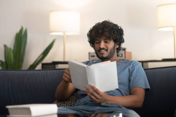 istock Curly-haired indian guy reading a book and looking involved 1407353845