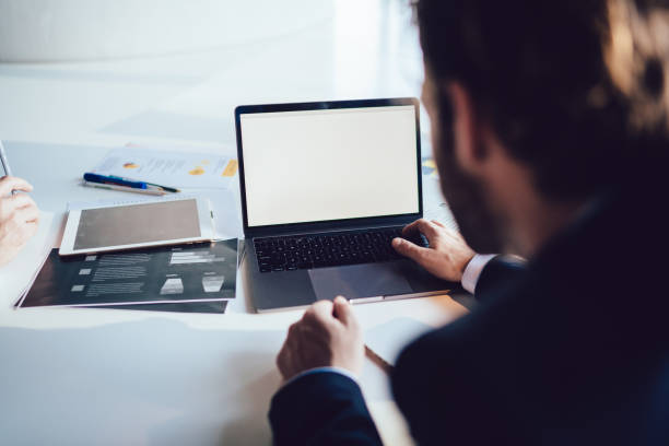 istock Faceless businessman using laptop with colleague in office 1407354604