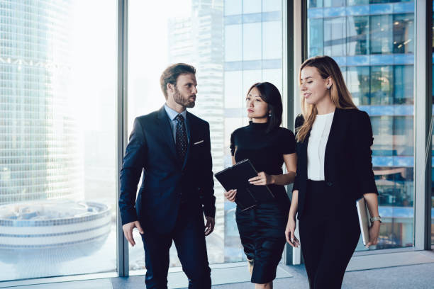 istock Multiracial elegant coworkers standing in modern workplace discussing business 1407354610