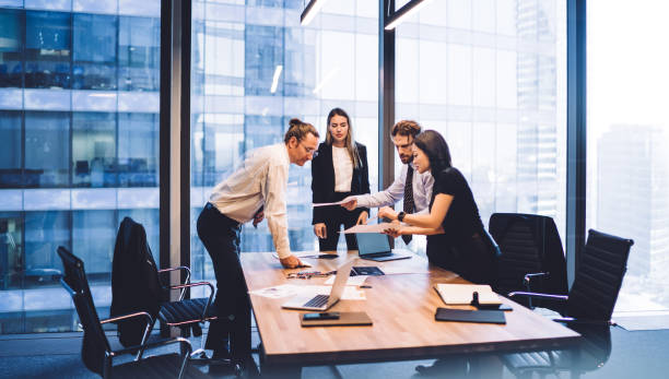 Male and female professionals teamworking during brainstorming cooperation on paper documents, group of diverse employers discussing corporate investment of firm capital briefing in conference room