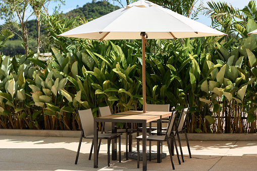 cafe on the beach surrounded by tropical greenery. summer cafe on the street. cafe outdoor furniture under sun umbrella. summer holiday concept. open beach umbrella in an outdoor bar on a sunny day