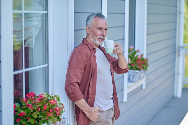 istock Gray-haired man having coffee on his house terrace 1407355768
