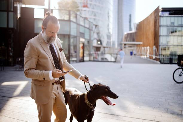 istock Mature man using phone while walking his dog in the city 1407358230