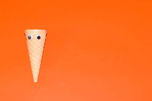 istock ice cream cone with eyes on the left side of orange background, creative summer design 1407359614