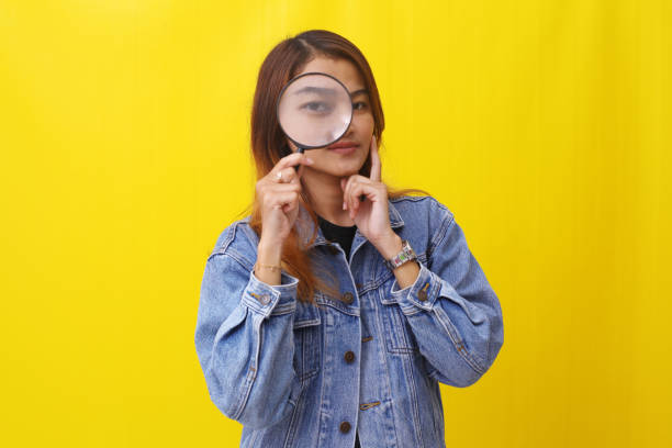 istock Young asian woman standing while looking through magnifying glass. Investigation concept 1407360097