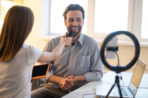 istock Long-haired woman holding a microphone while a smiling bearded man talking 1407360354